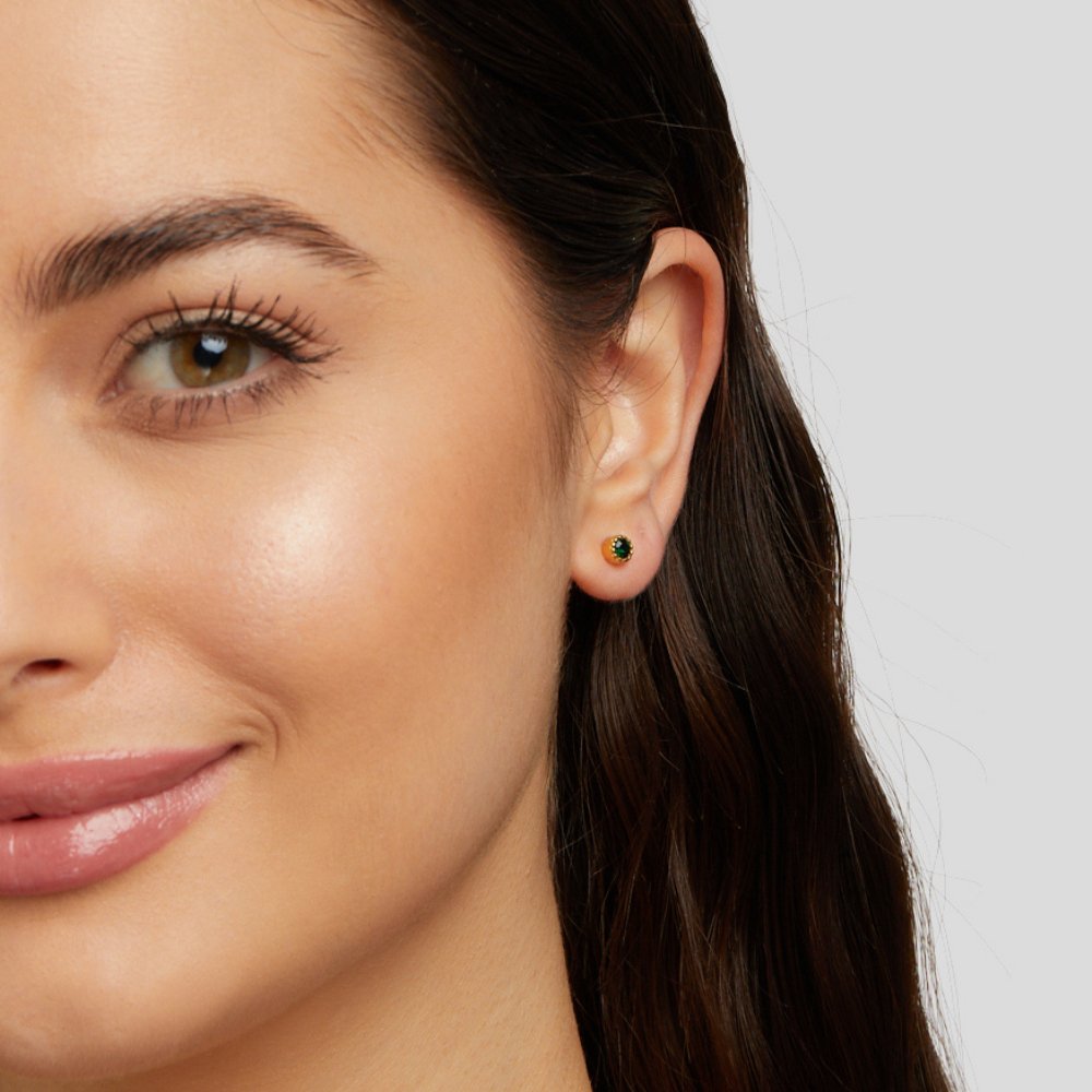 Emerald Green Stud Earrings, worn on an ear of a model with long dark hair