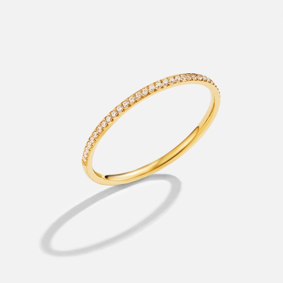 Eternity 18K Crystal Ring, thin gold band with a row of small stones, on a plain background