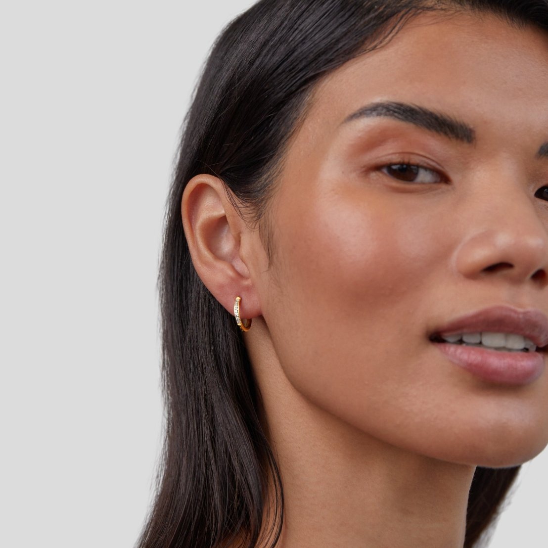 Eternity Hoop Earrings, worn on a model's ear, close-up with gold hoop and small stones