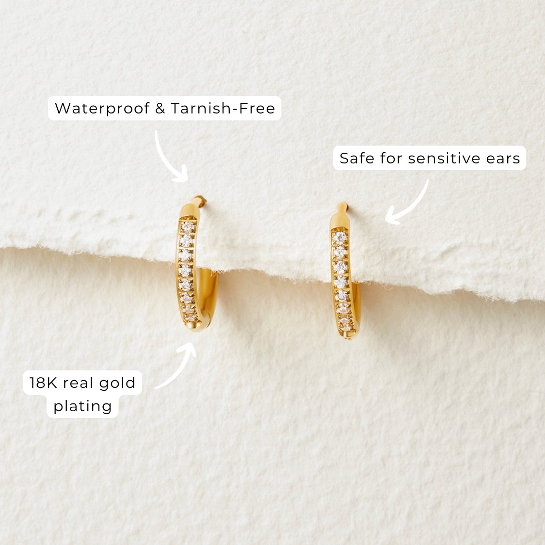 Eternity Hoop Earrings, two small gold hoop earrings with a row of clear stones, on textured paper