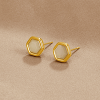 Eva Moonstone Stud Earrings, a pair of hexagonal gold studs lying on beige fabric, pale stones