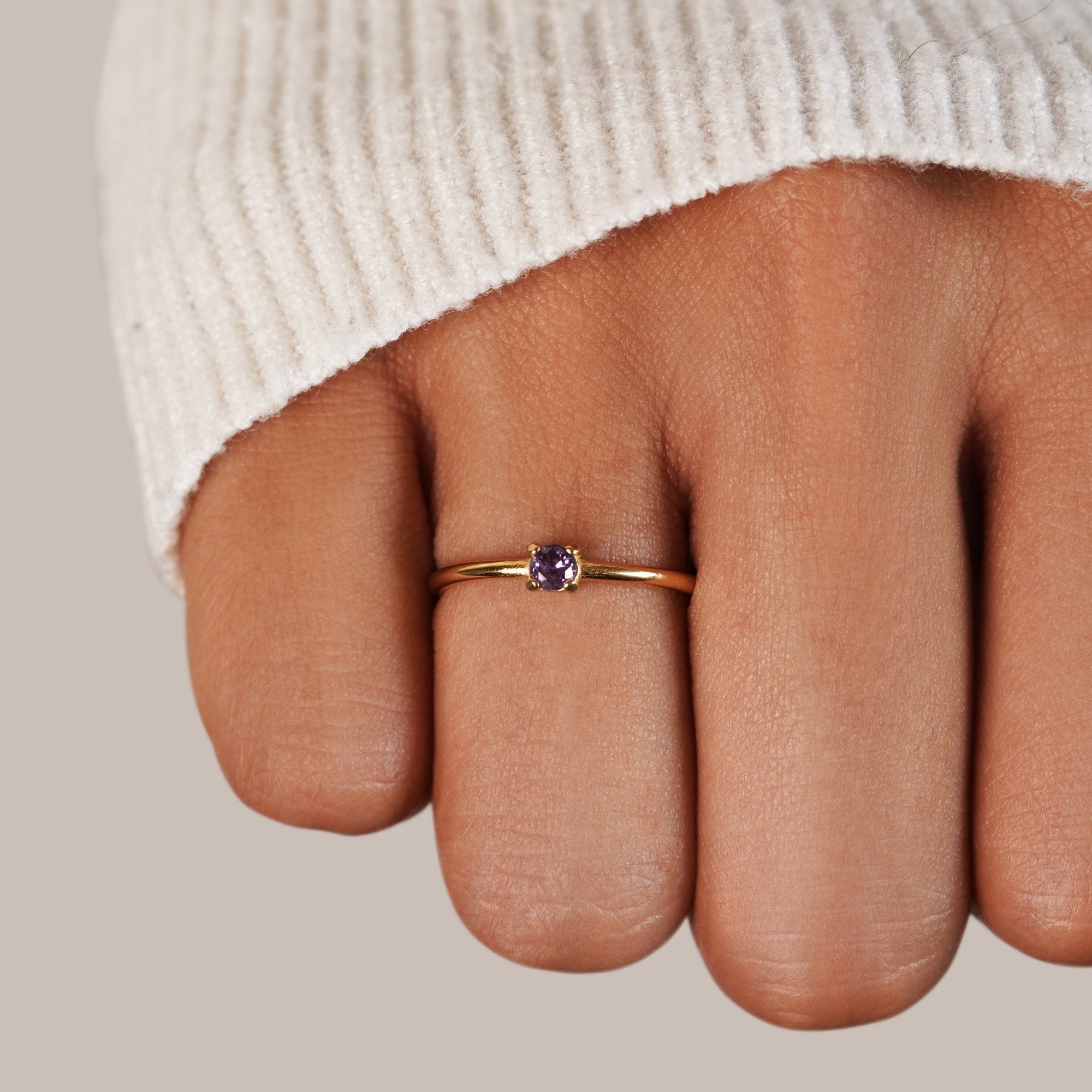 February Birthstone 18K Gold Ring, worn on a finger with a cream knit sleeve, close-up on
