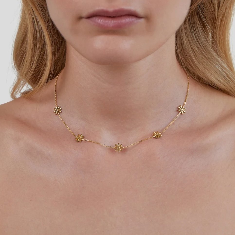 Flower Power 18K Gold Necklace, worn on a neck, with five small gold flower charms on a fine chain