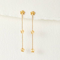 Flower Power Petal Drop Earrings, pair of gold flower drop earrings hanging on white textured