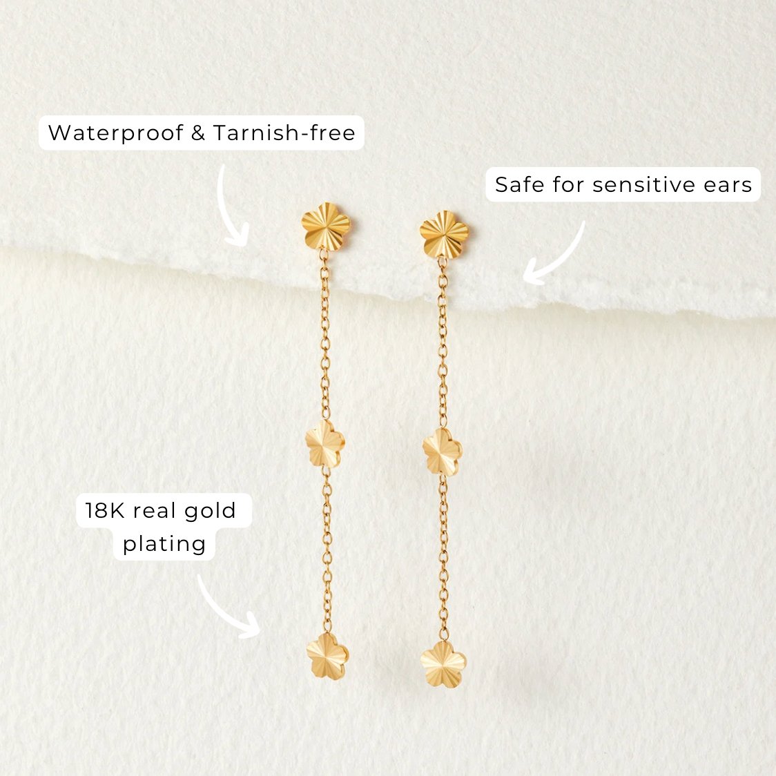 Flower Power Petal Drop Earrings, pair of gold flower drop earrings on a pale textured background