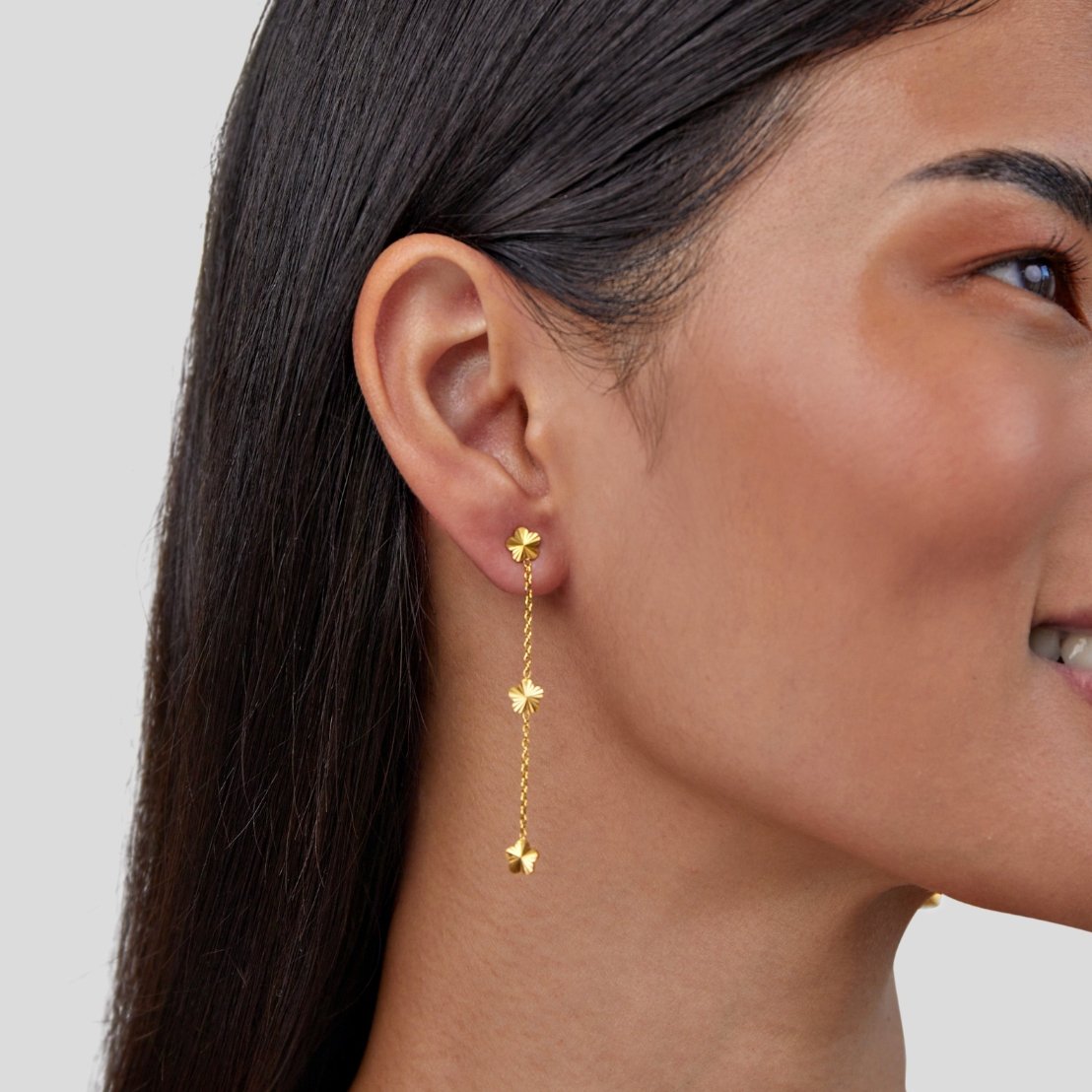 Flower Power Petal Drop Earrings, worn on an ear, gold flowers along a long chain drop