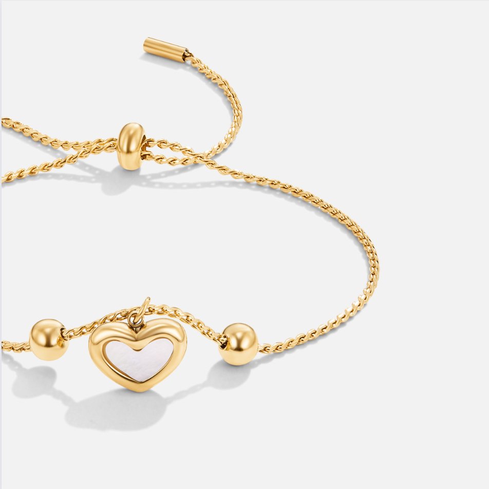 Forever Love Heart Bracelet, flat lay of gold bracelet with white heart charm on grey background