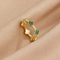 Four Leaf Clover Crystal Ring, gold band with green clover motifs on beige fabric