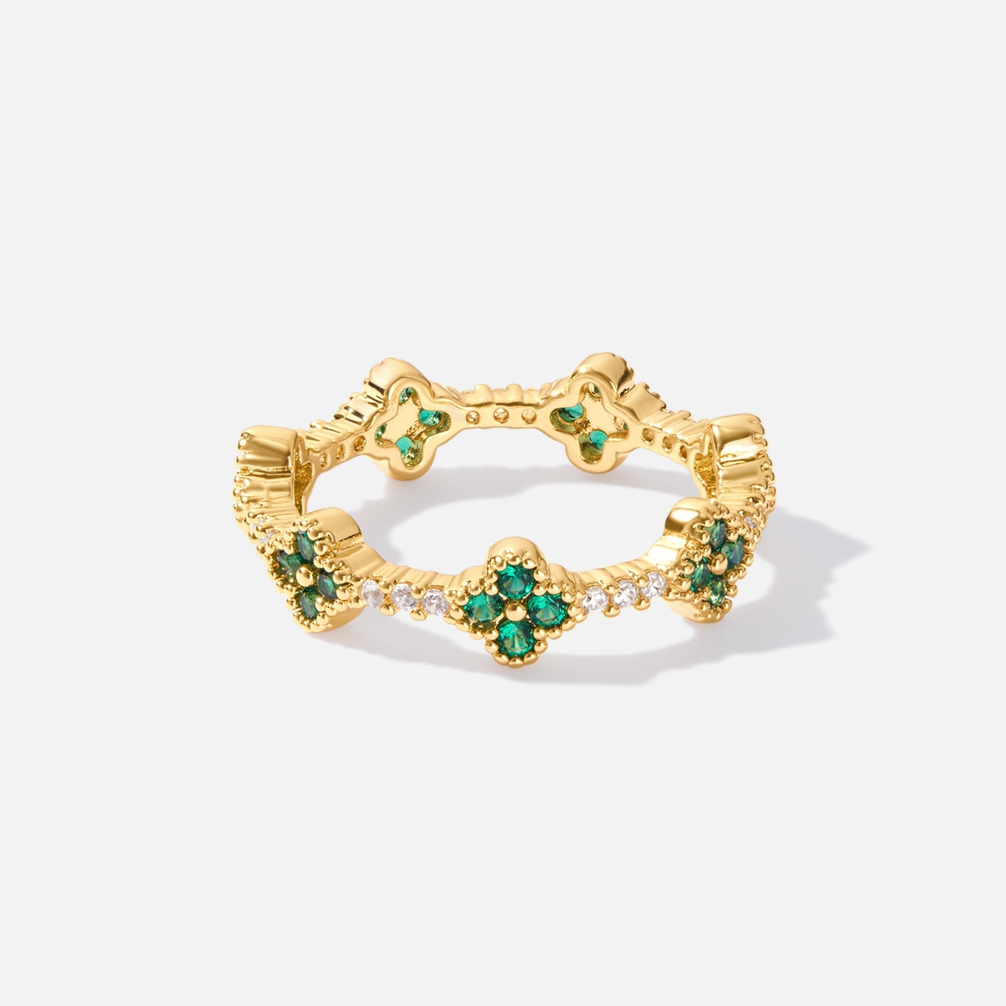 Four Leaf Clover Crystal Ring, gold band with green clover motifs and clear stones, on white