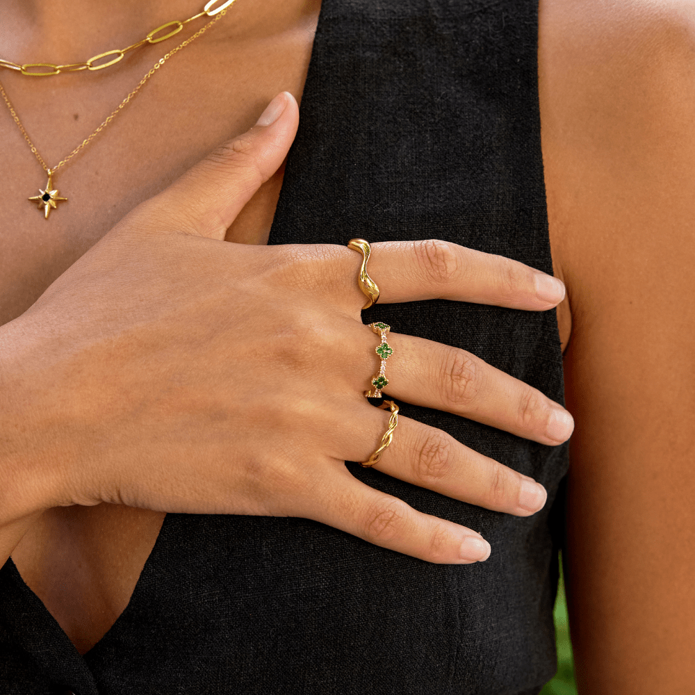Four Leaf Clover Crystal Ring, worn on a hand with gold rings and layered necklaces