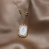 'Fragile Love' Rose Necklace, laid on draped satin, pendant with an engraved white rose