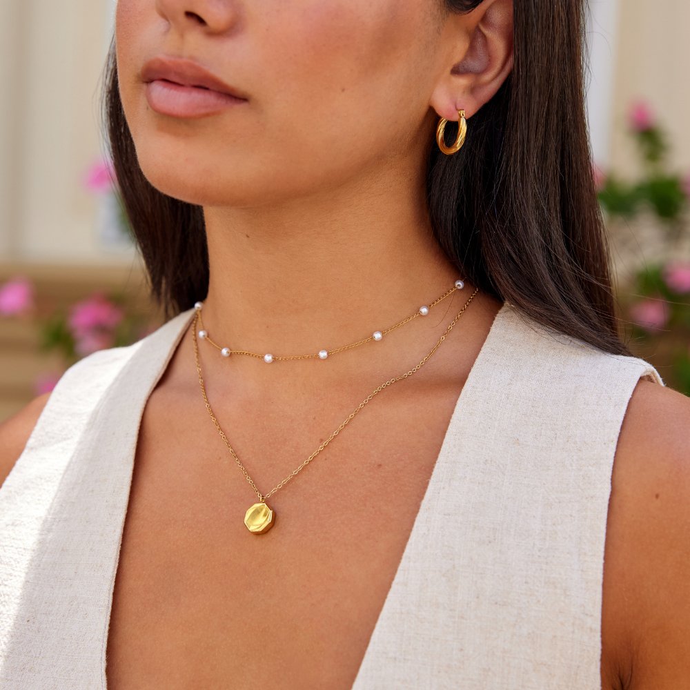 Geometric Pendant Necklace, worn on a neck with a pearl chain and gold hoop earring