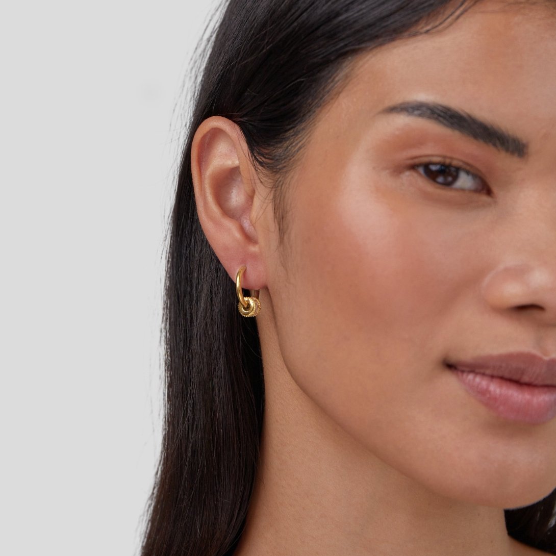 Gigi Crystal 18K Gold Hoop Earrings, worn on an ear by a model with long dark hair