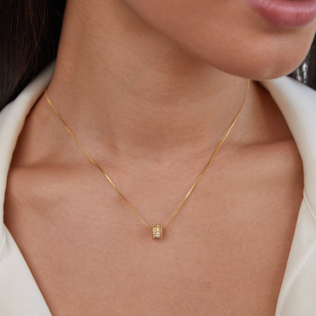 Gigi Crystal 18K Gold Necklace, worn on a neck with a white collared top, close-up on the pendant