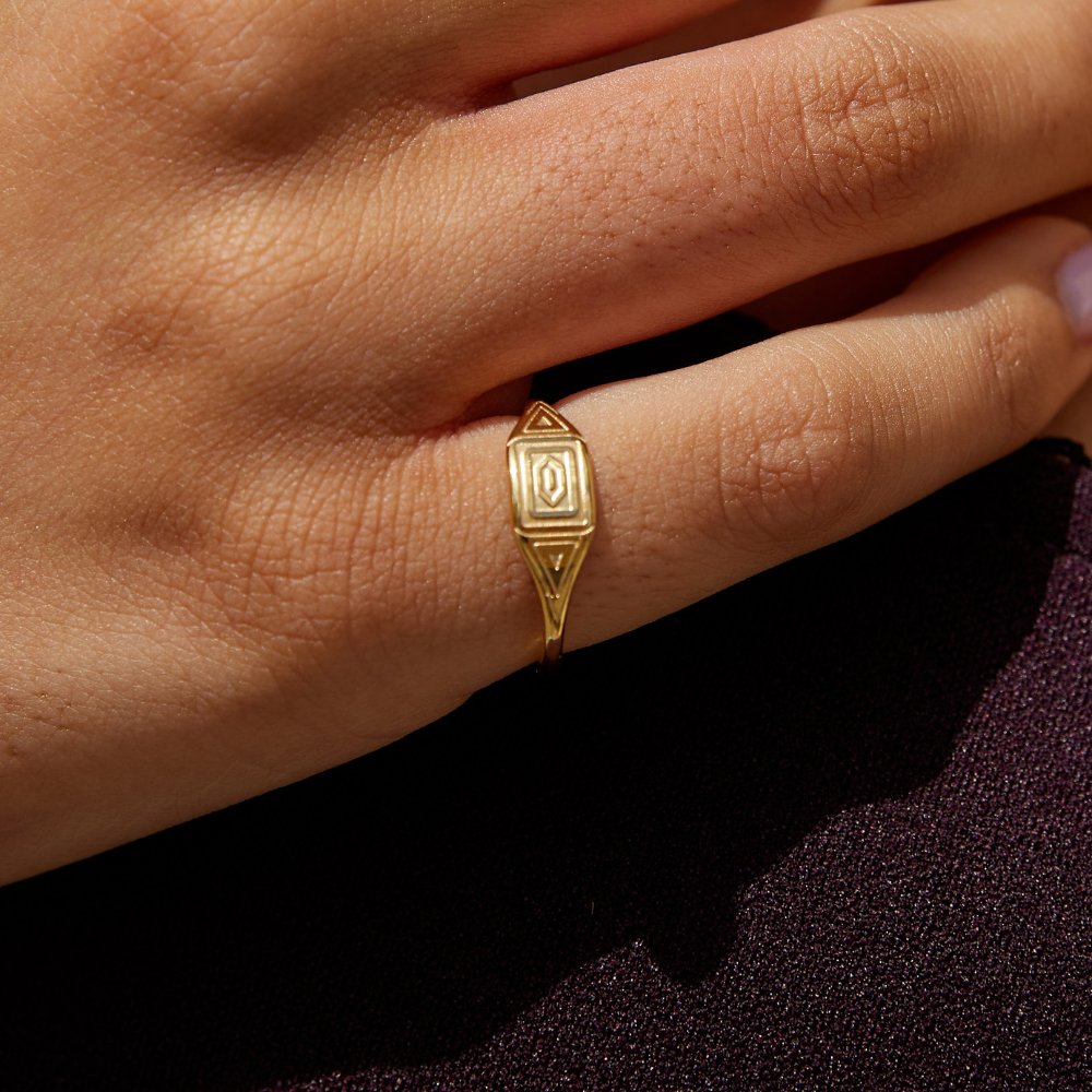 Gold Adaline Ring, worn on a hand over dark fabric, close-up of gold geometric face