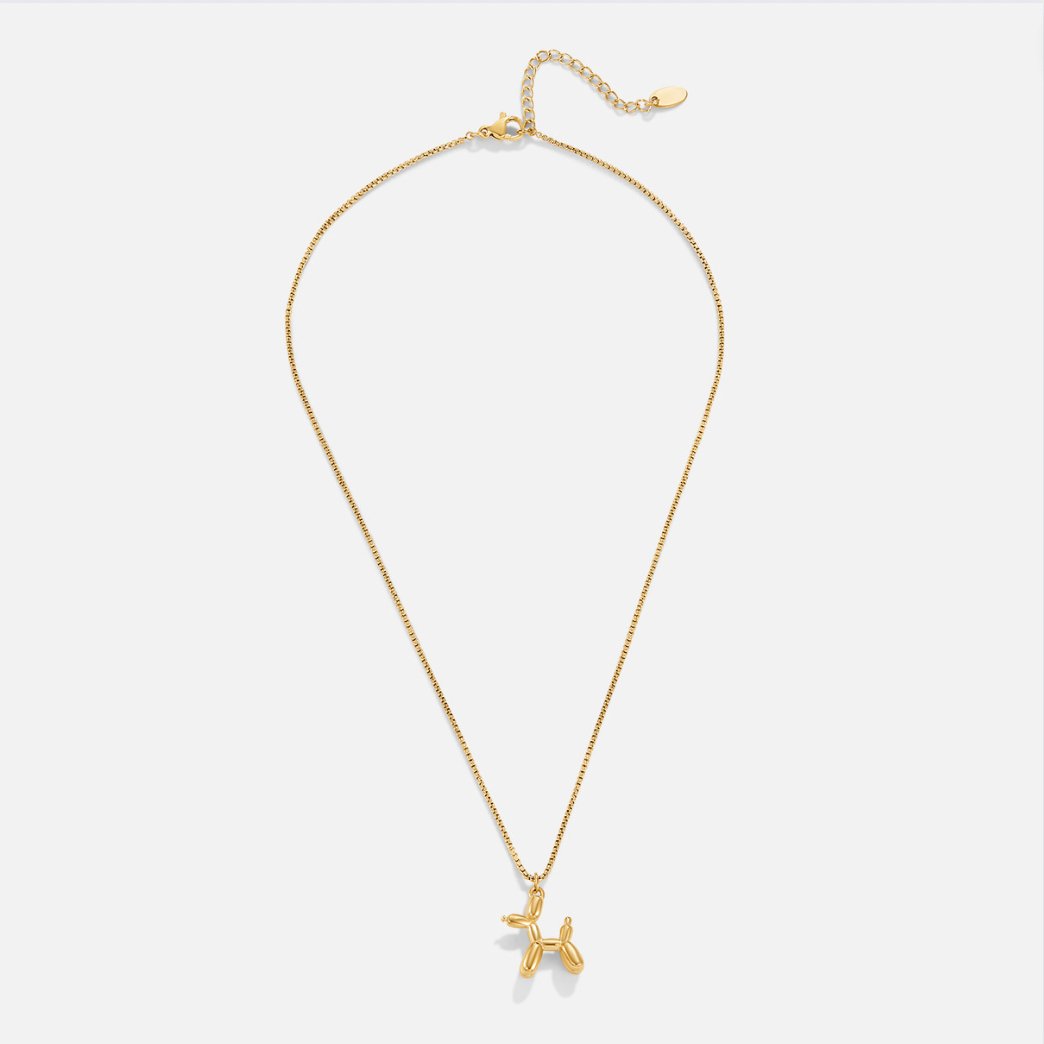 Gold Balloon Animal Necklace, laid flat on light grey, gold chain with balloon dog pendant