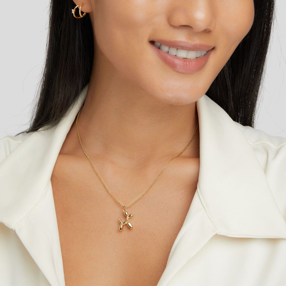 Gold Balloon Animal Necklace, worn on a smiling model in a white collared top