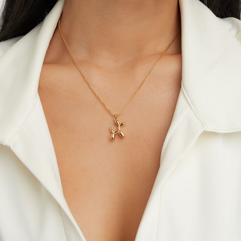 Gold Balloon Animal Necklace, worn on a neck with a white open-collar shirt