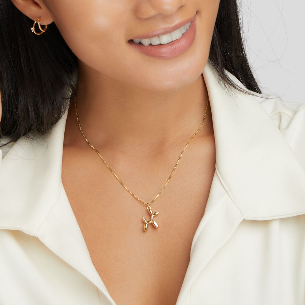 Gold Balloon Animal Necklace, worn on a smiling model in a cream collared blouse