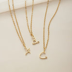 Gold Letter Heart Necklace, three gold chain necklaces laid flat with letter pendants A, B and C