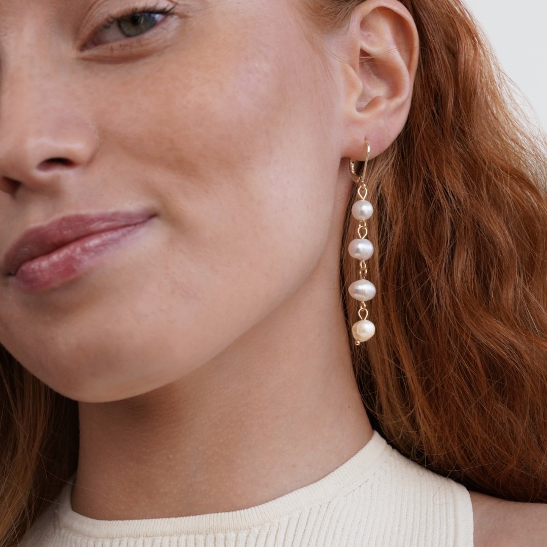 Golden Freshwater Pearl Earrings, worn on an ear, four pearls on a long gold drop