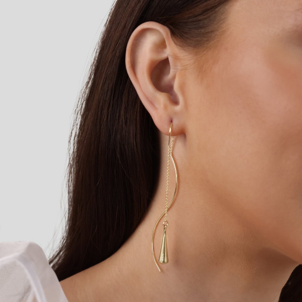 Golden Teardrop Tassel Earrings, worn on an ear with a long curved gold drop