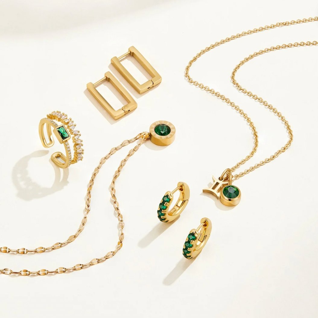 Green Crystal Athena Necklace, flat lay of gold rings, earrings and necklaces with green stones
