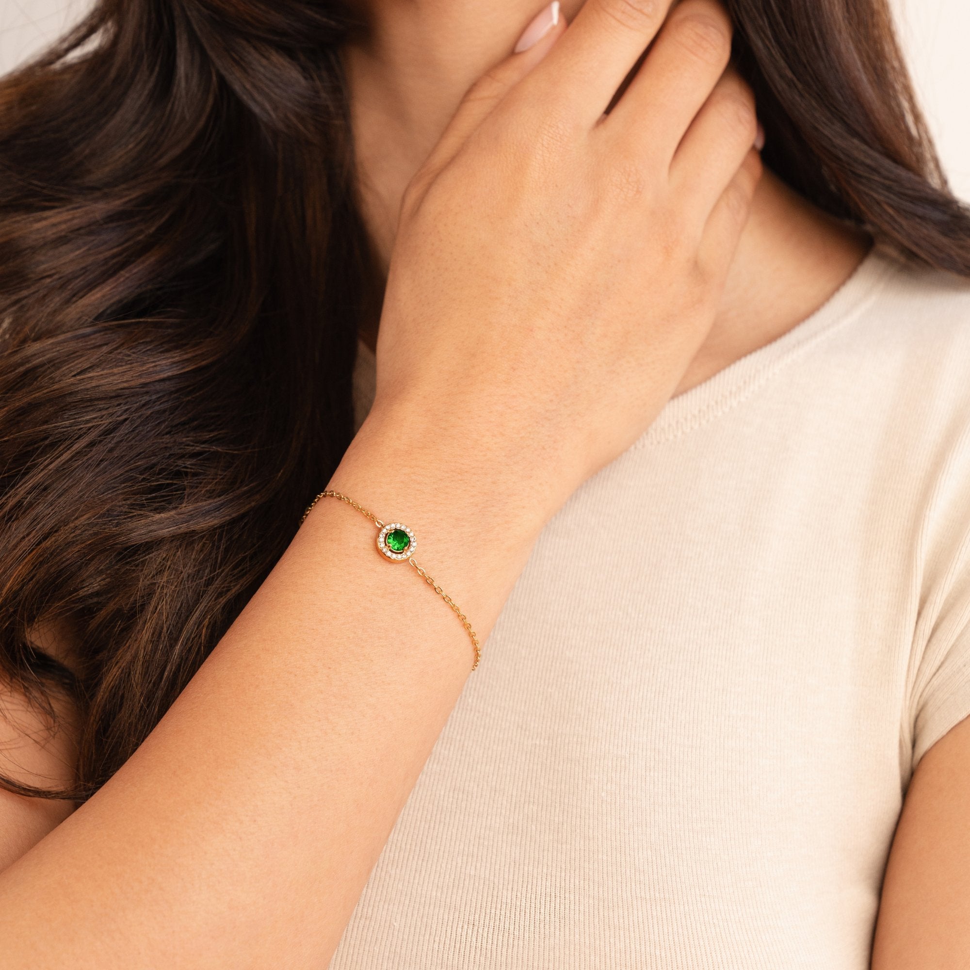 Green Emerald Crystal Bracelet, worn on a wrist with a hand raised to the neck, green centre stone