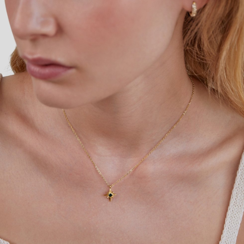 Guiding Star Emerald Crystal Necklace, worn on a neck with a gold hoop earring and white top