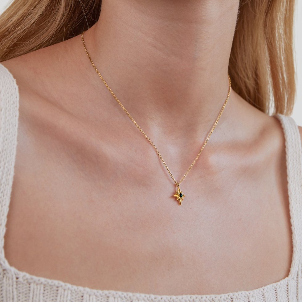 Guiding Star Emerald Crystal Necklace, worn on a neck with a white knit top, small green stone