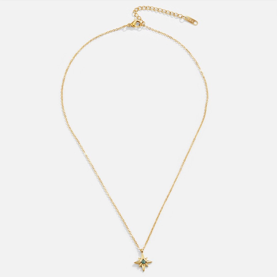Guiding Star Emerald Crystal Necklace, laid flat on a light background, gold chain with star