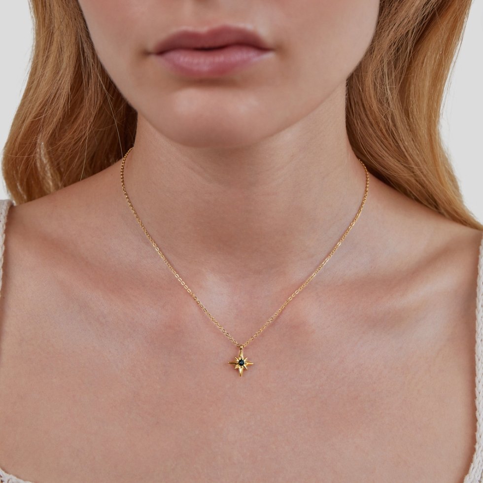 Guiding Star Emerald Crystal Necklace, worn on a neck with a fine gold chain and a dark blue