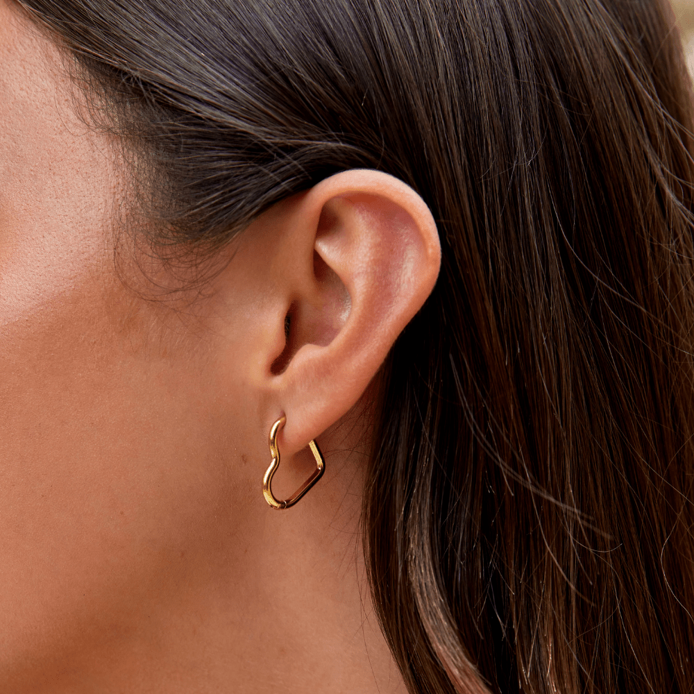 Heart Gold Hoops, worn on an ear of a model with dark hair, close-up