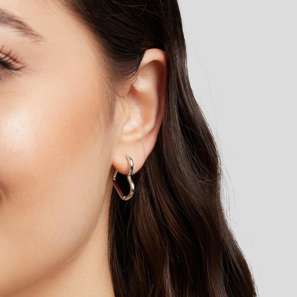 Heart Silver Hoops, worn in an ear, close-up of a wavy heart-shaped hoop