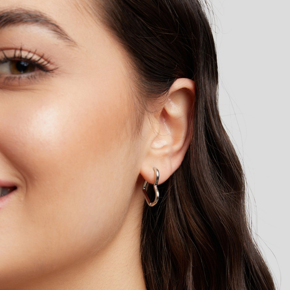 Heart Silver Hoops, worn on an ear, close-up of a wavy silver hoop