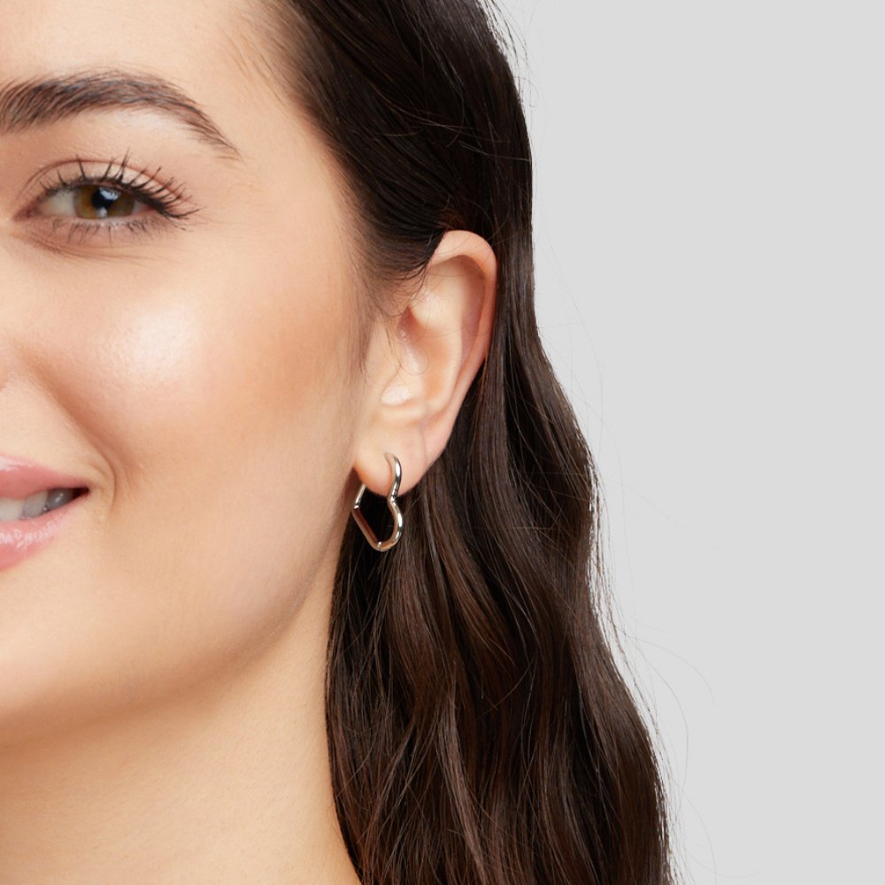 Heart Silver Hoops, worn on an ear of a model with dark wavy hair