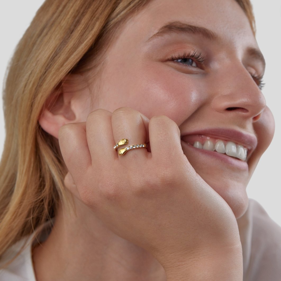 'Hug Me Forever' 18K Gold Ring, worn on a hand resting against a smiling cheek, gold and