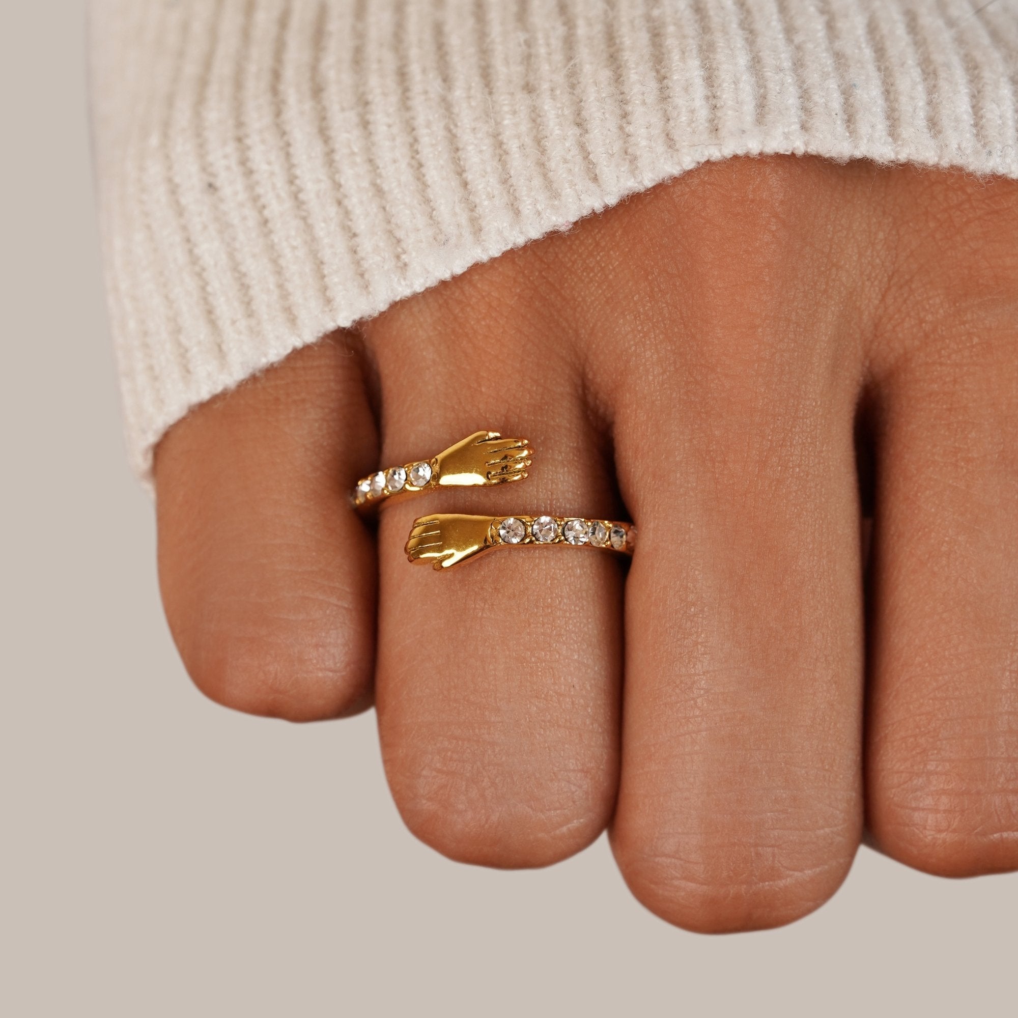 'Hug Me Forever' 18K Gold Ring, worn on a finger with a cream knit sleeve behind it