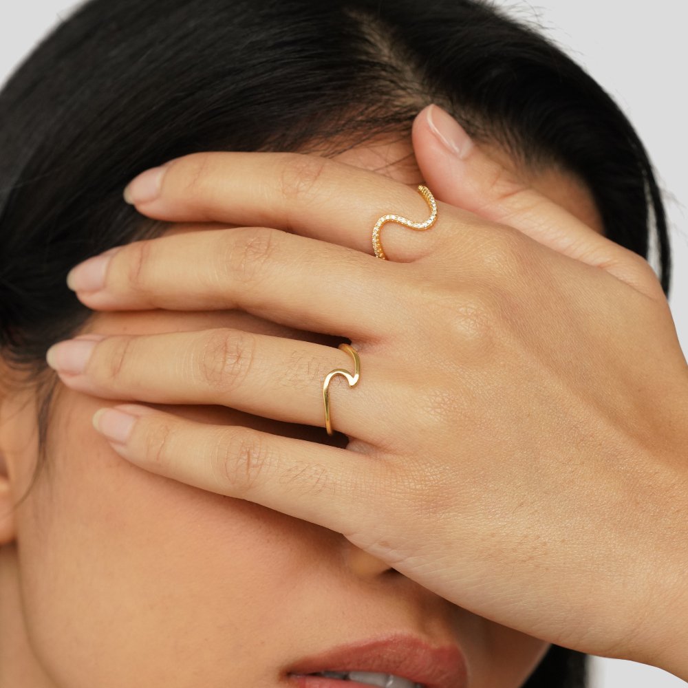 Imari Gold Wave Ring, worn on a hand covering face, gold wave rings on two fingers