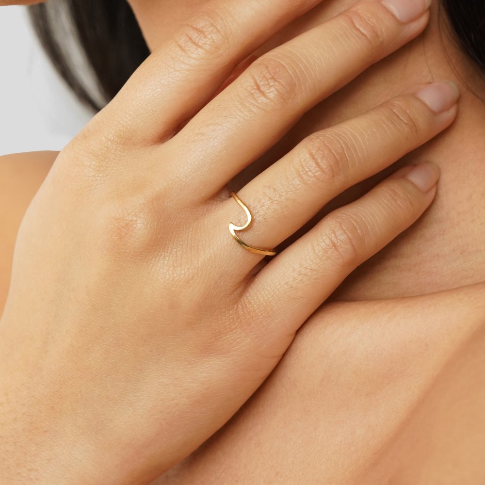 Imari Gold Wave Ring, worn on a hand resting near the neck, gold wave design