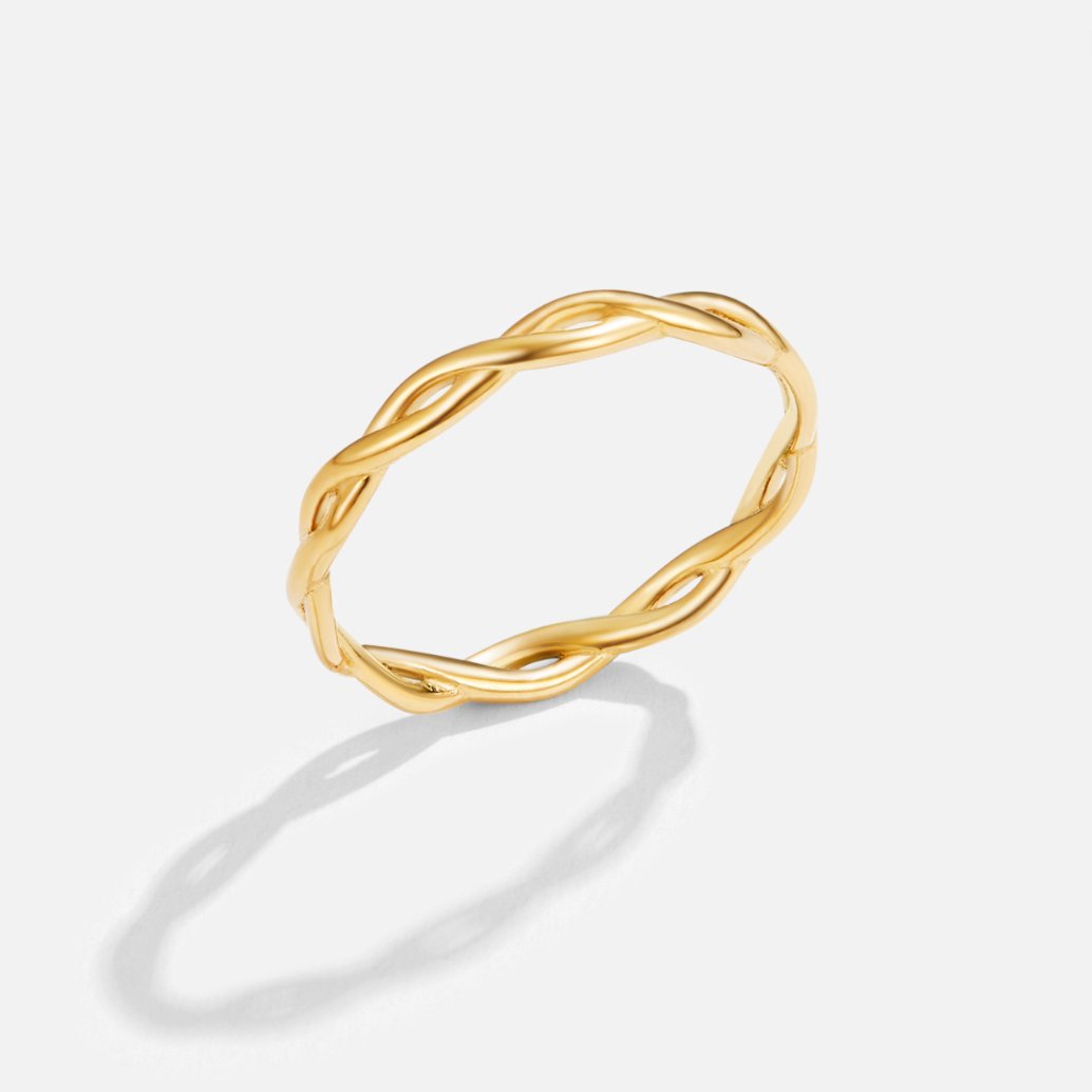 Infinity 18K Gold Twist Ring, standing upright on a white surface, twisted gold band with a shadow