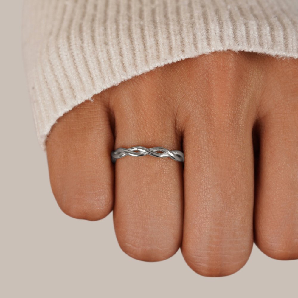 Infinity 18K Silver Twist Ring, worn on a hand with a cream knit sleeve, twisted silver band