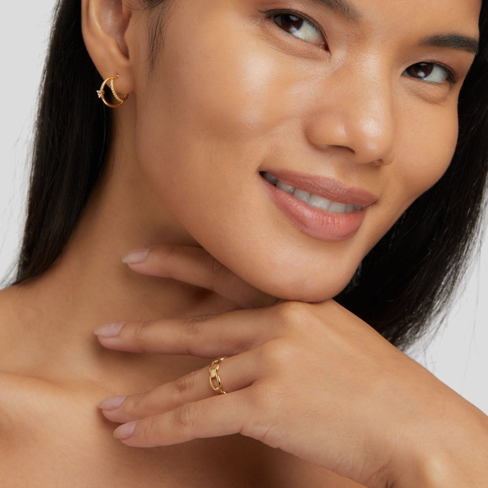 Isabella Chain Ring, worn on a hand resting by a smiling model's chin, with a gold hoop earring