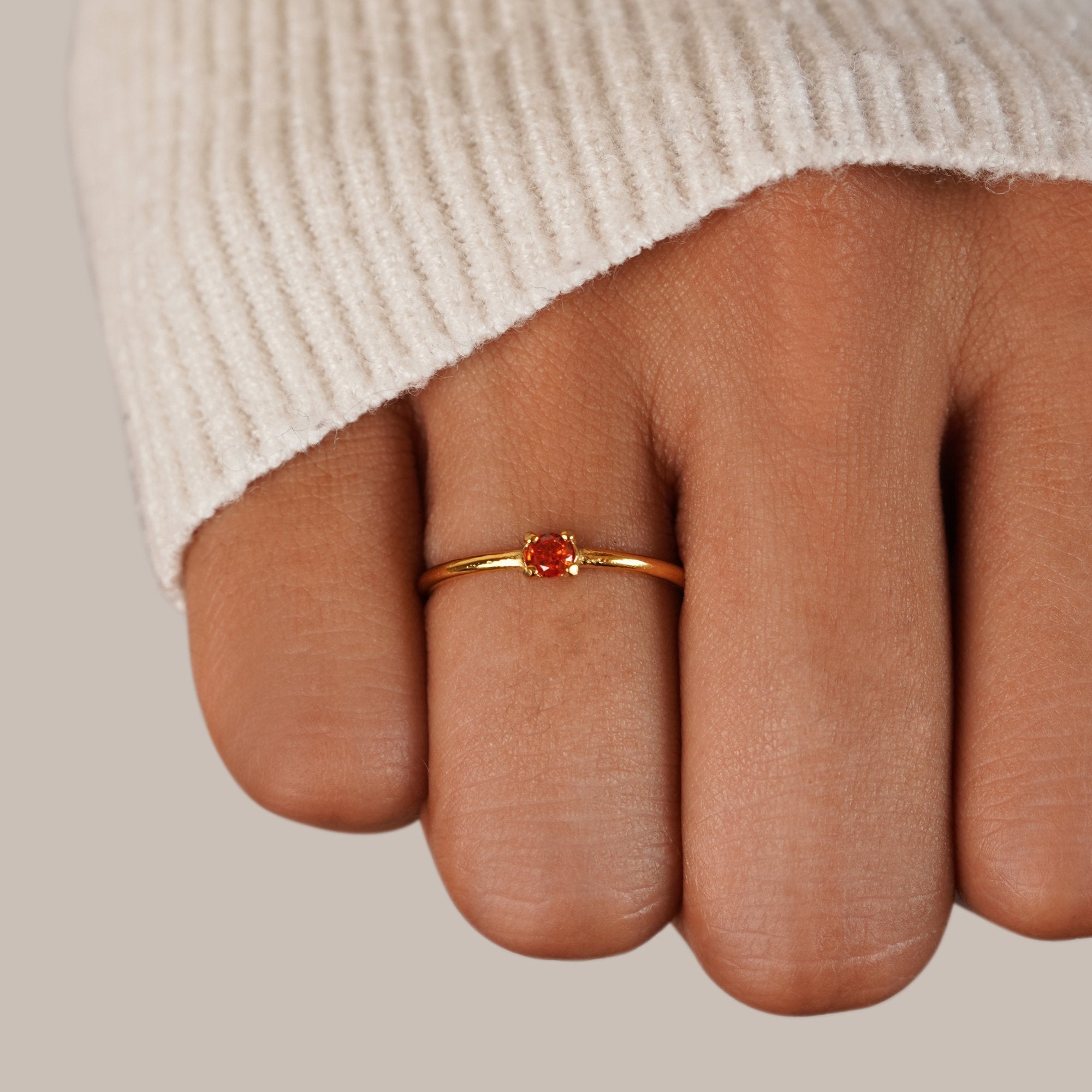 July Birthstone 18K Gold Ring, worn on a hand in a cream knit sleeve, red stone in gold