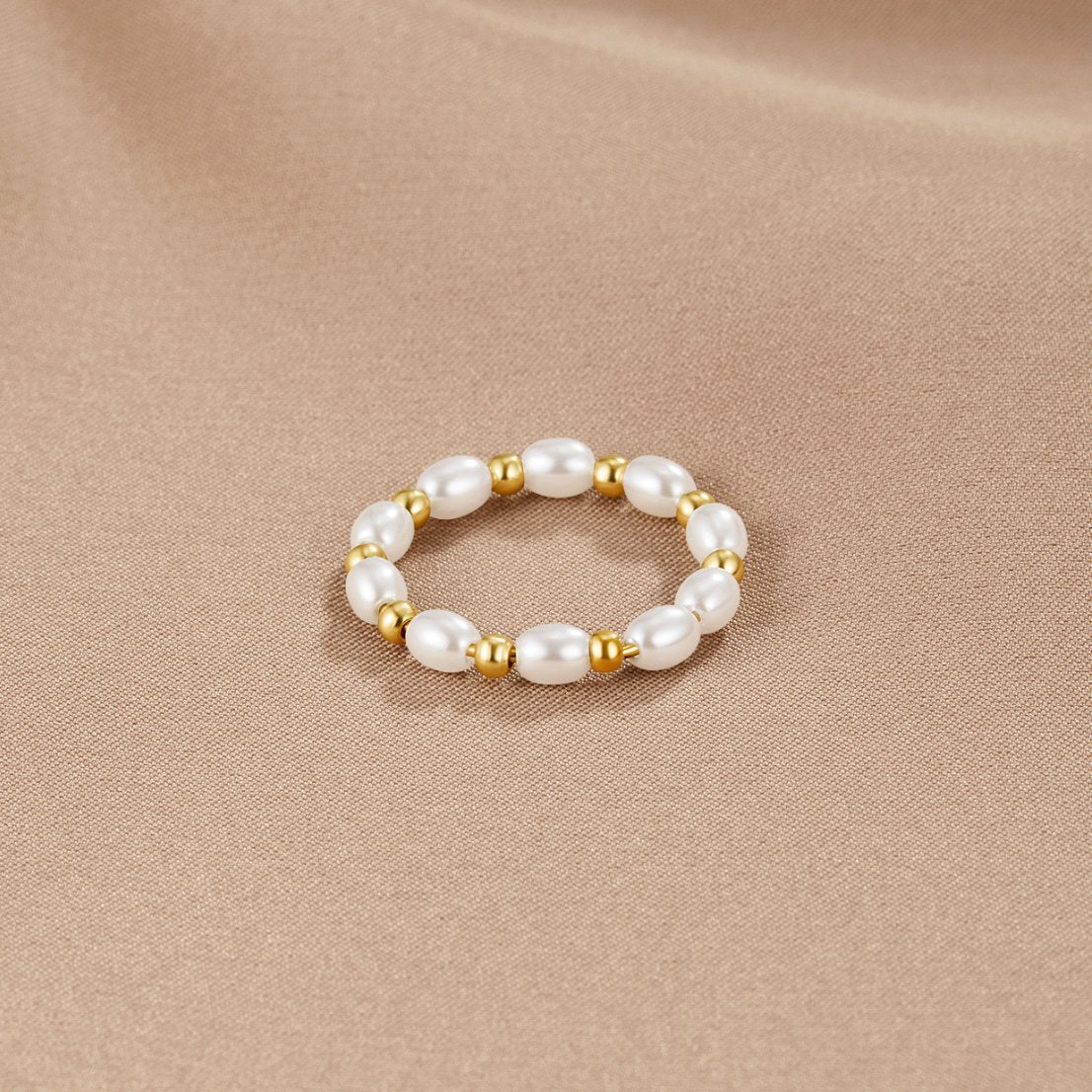 Kai Mini Pearl Ring, ring lying flat on a beige satin cloth, pearls alternating with gold beads