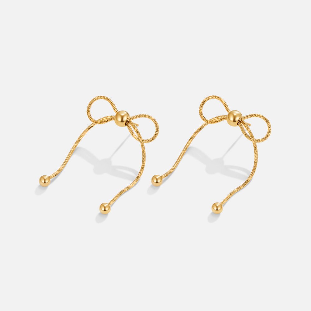 Katie Bow Earrings, pair of gold bow earrings with ball-tipped tails on a plain background