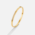 Kim Crystal bangle, gold bangle on a light grey background, with a row of small crystals