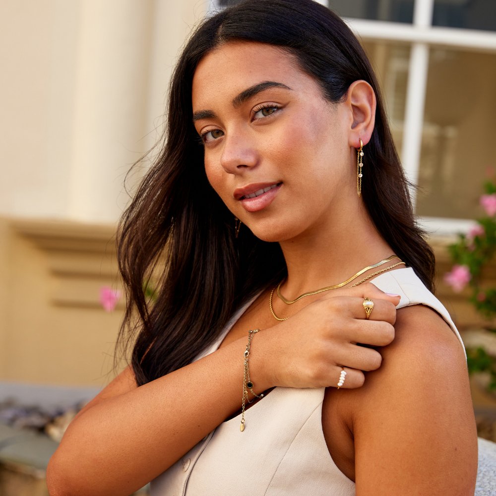 Kira Crystal Drop Hoop Earrings, worn by a model with layered gold necklaces, bracelet and rings