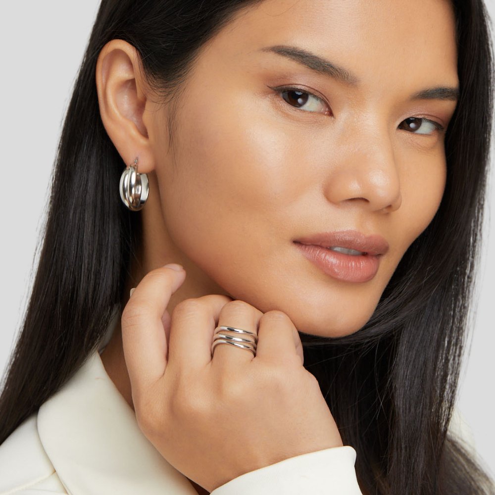 Kiya Layered Silver Ring, worn on a hand at the chin, with a matching silver hoop earring