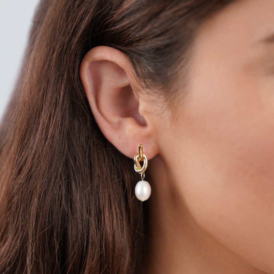 Knotted Gold & Freshwater Pearl Earrings, worn on an ear, gold knot with a white pearl drop